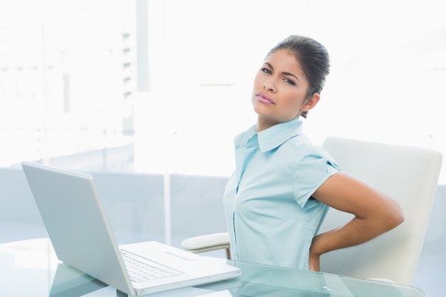 Businesswoman suffering from back ache in office