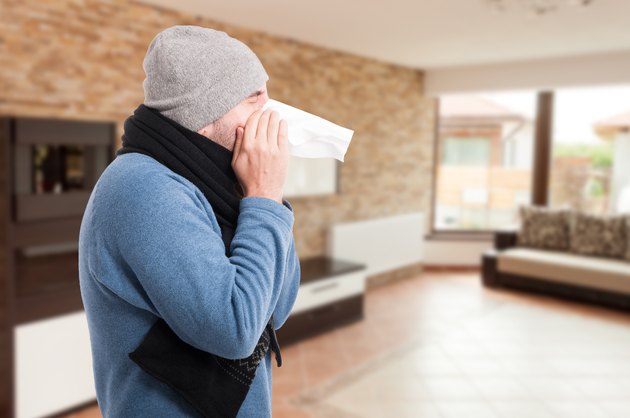 Young man blowing nose into a tissue
