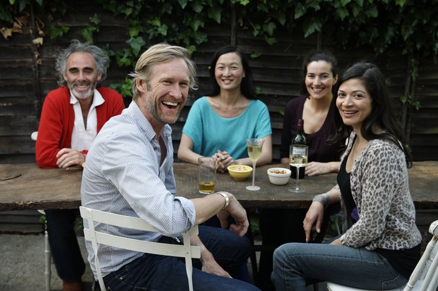 Group portrait of five friends sitting at table in garden