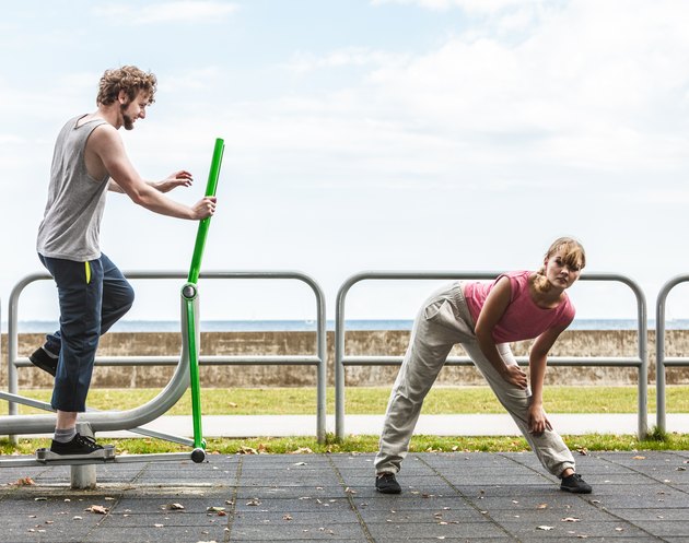 Man exercising on elliptical trainer and woman.