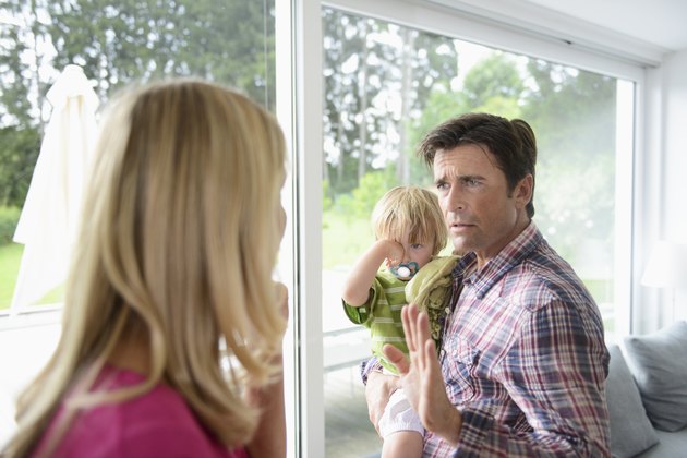 Mature man holding son in argument with woman