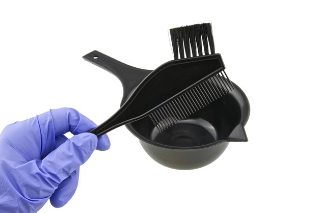 Man wear purple latex glove holding back brush over bowl