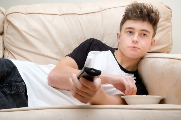 Teenage Boy Laying On A Sofa Watching TV