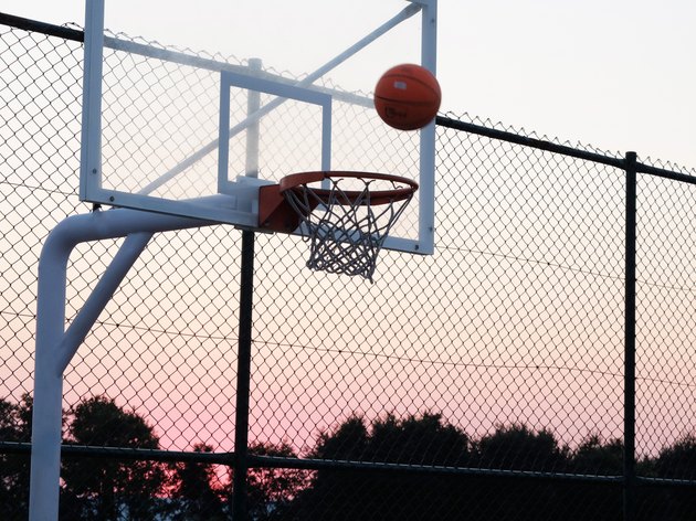 Basketball hoop with a ball at sunset.