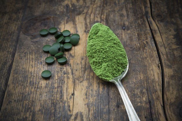Spoon of wheatgrass powder and wheatgrass tablets