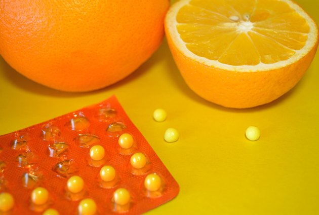 Oranges and vitamin C on yellow background