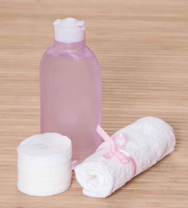 Cleansing face tonic with a towel and cotton pads on wooden surface