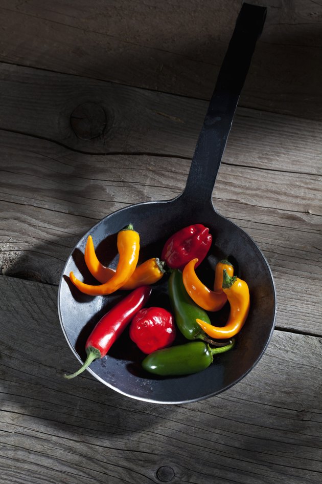 Habanero, Jalalpeno and chili peppers in frying pan on wood