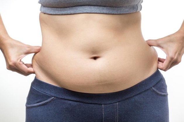 overweight woman with hand holding fat belly