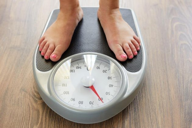 Female bare feet with weight scale on the wooden floor
