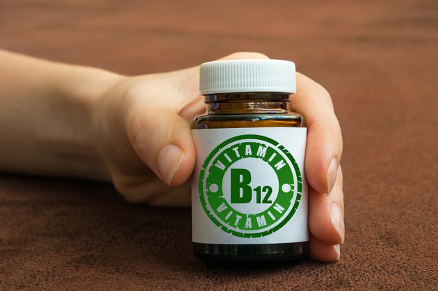 Human hand holding a bottle of pills with vitamin B12