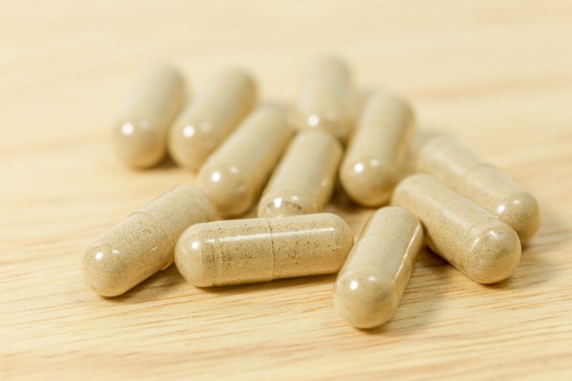 Herbal medicine pills on wood board.