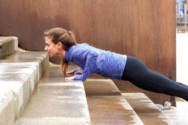 Portrait of serious female athlete in push up on staircase
