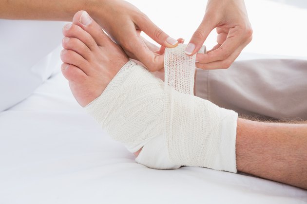 Doctor bandaging her patient leg