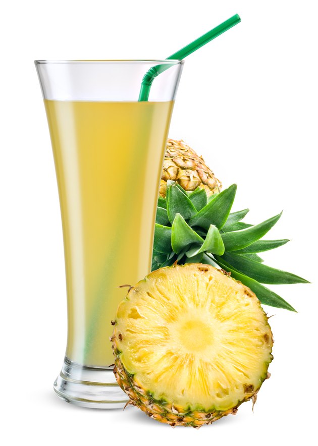 Glass of pineapple juice with fruit isolated on white.