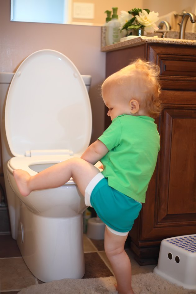 Baby trying to sit on a toilet