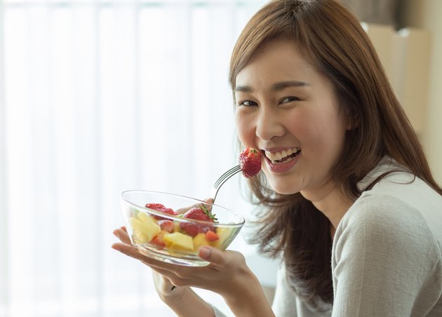 Asian woman is happily eating her fruit salad