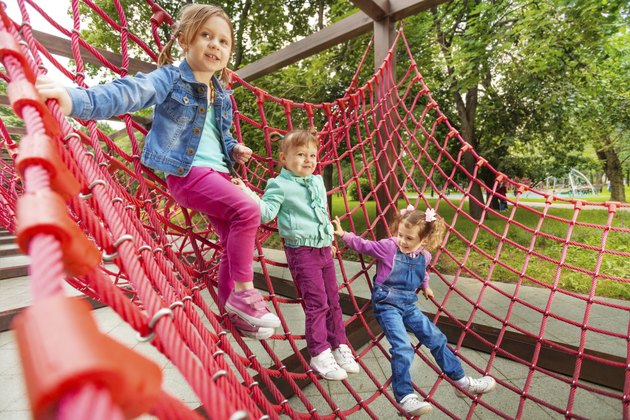 Three small girl sitting on red grid in summer