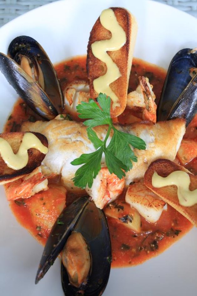 Bouillabaisse with muscles, prawns, fish, red sauce and bread.