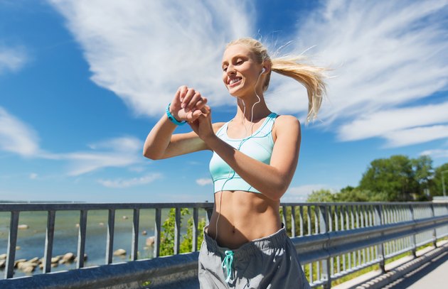 happy woman with heart rate watch and earphones