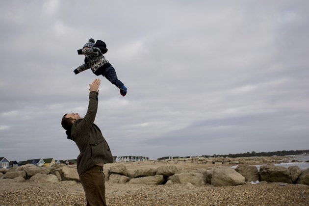 Father throwing son in the air at the beach
