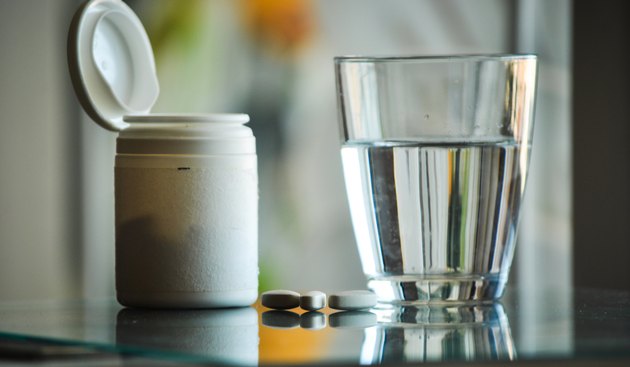 pills with pill bottle and glass of water