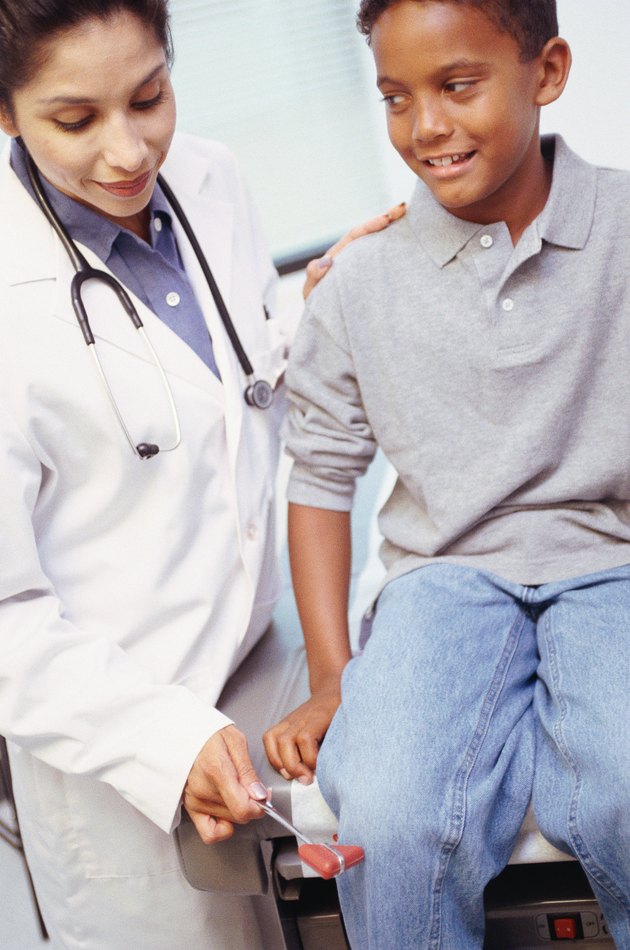 Female doctor testing boy's reflexes