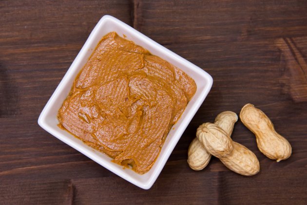 Bowl with peanut butter on wood from above