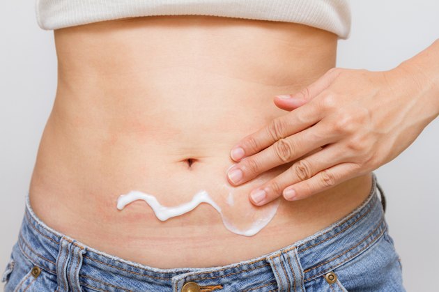 Woman apply body cream.