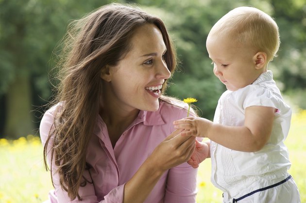 Happy mother giving flower to baby in the park
