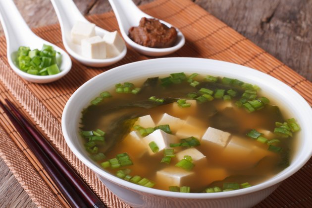 Japanese miso soup in bowl and ingredients close-up.
