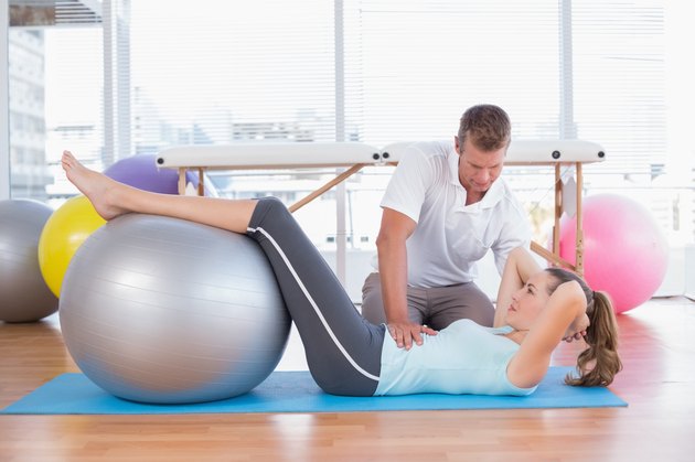 Trainer working with woman on exercise mat