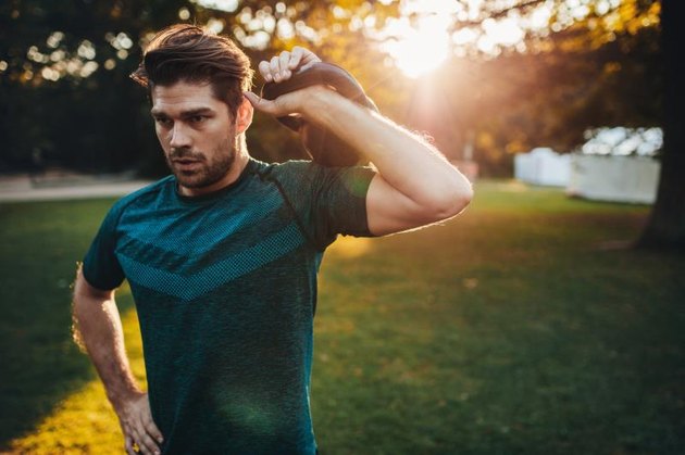 Portrait of strong young man exercising with kettlebell. Fit and muscular man training at park in morning.