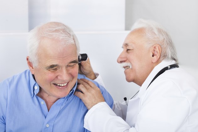 Doctor Examining Senior Man's Ear With Otoscope