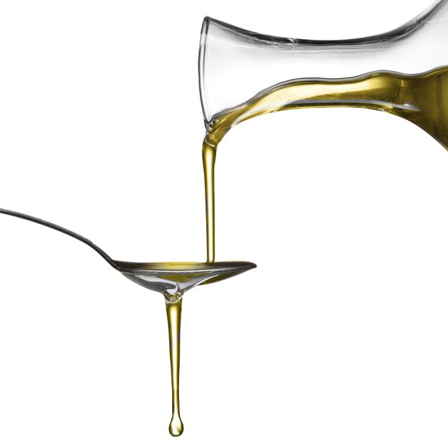 Pouring oil on spoon isolated