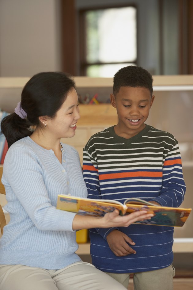 Female teacher and her student reading a book