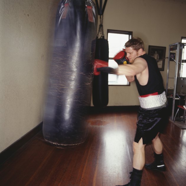 拳击手在体育馆用拳击袋训练，侧视图