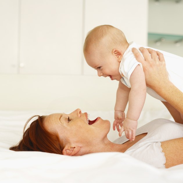side view of a mother lying on a bed holding her baby (6-12 months)