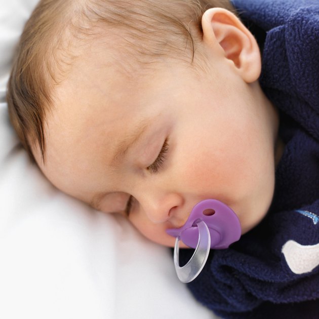 elevated close up view of a baby (6-12 months) sleeping with a dummy in its mouth
