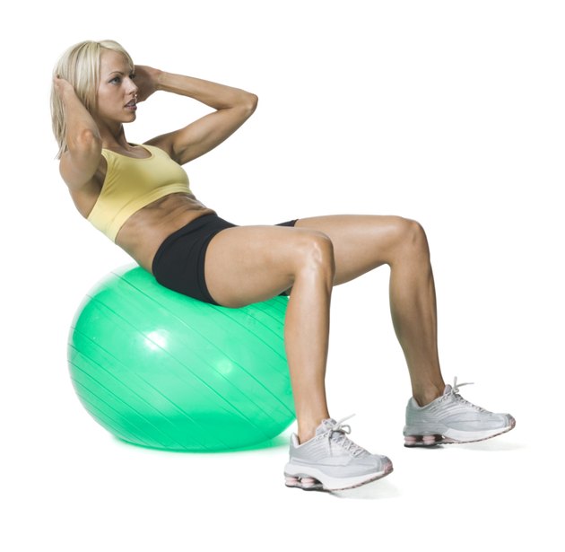 full body shot of a young woman in a yellow and black exercise outfit as she does sit ups on a green ball