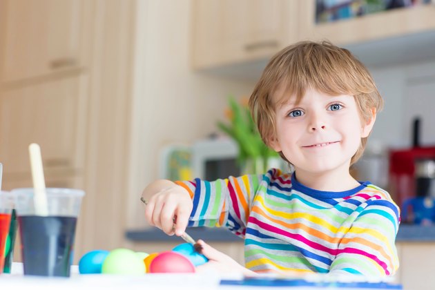 Little kid boy coloring eggs for Easter holiday