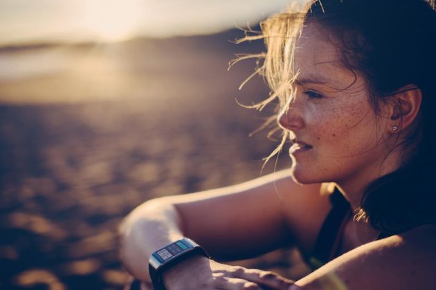 Portrait of a blond haired woman with smartwatch at the beach after running.