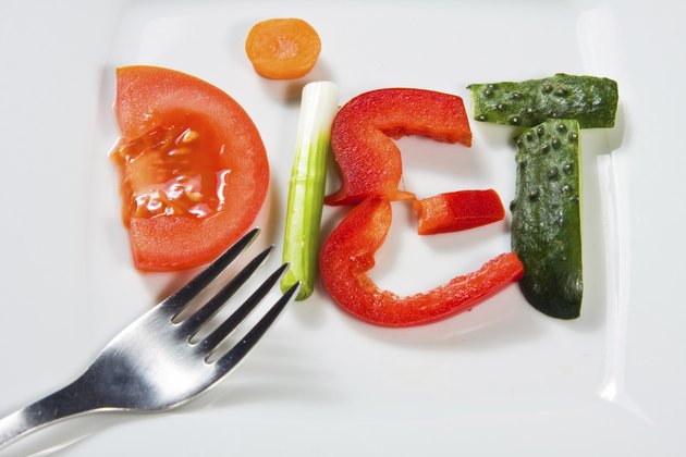 Plate with vegetables and word diet over wooden background