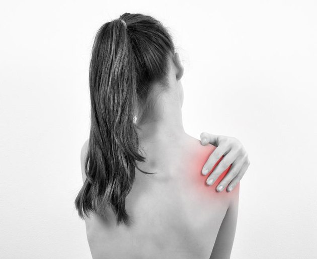 Girl having shoulder pain isolated on the white background. Black and white photo.