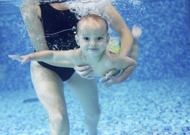 Little boy learning to swim in a swimming pool