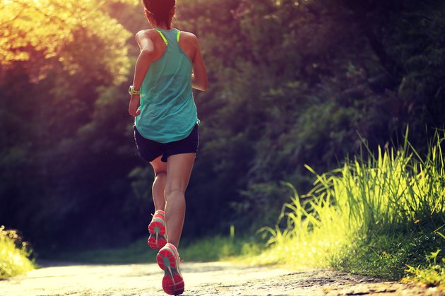 Runner athlete running on forest trail.