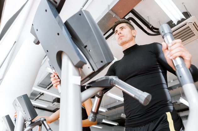 Young fit male working out on an elliptical trainer