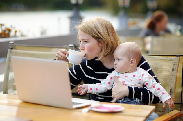 Young mother with her baby working or studying on laptop