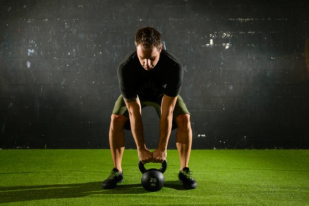 Athlete lifting heavy weight with Kettle-bell
