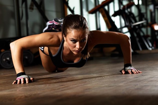 Sporty young woman doing a pushups at gym.